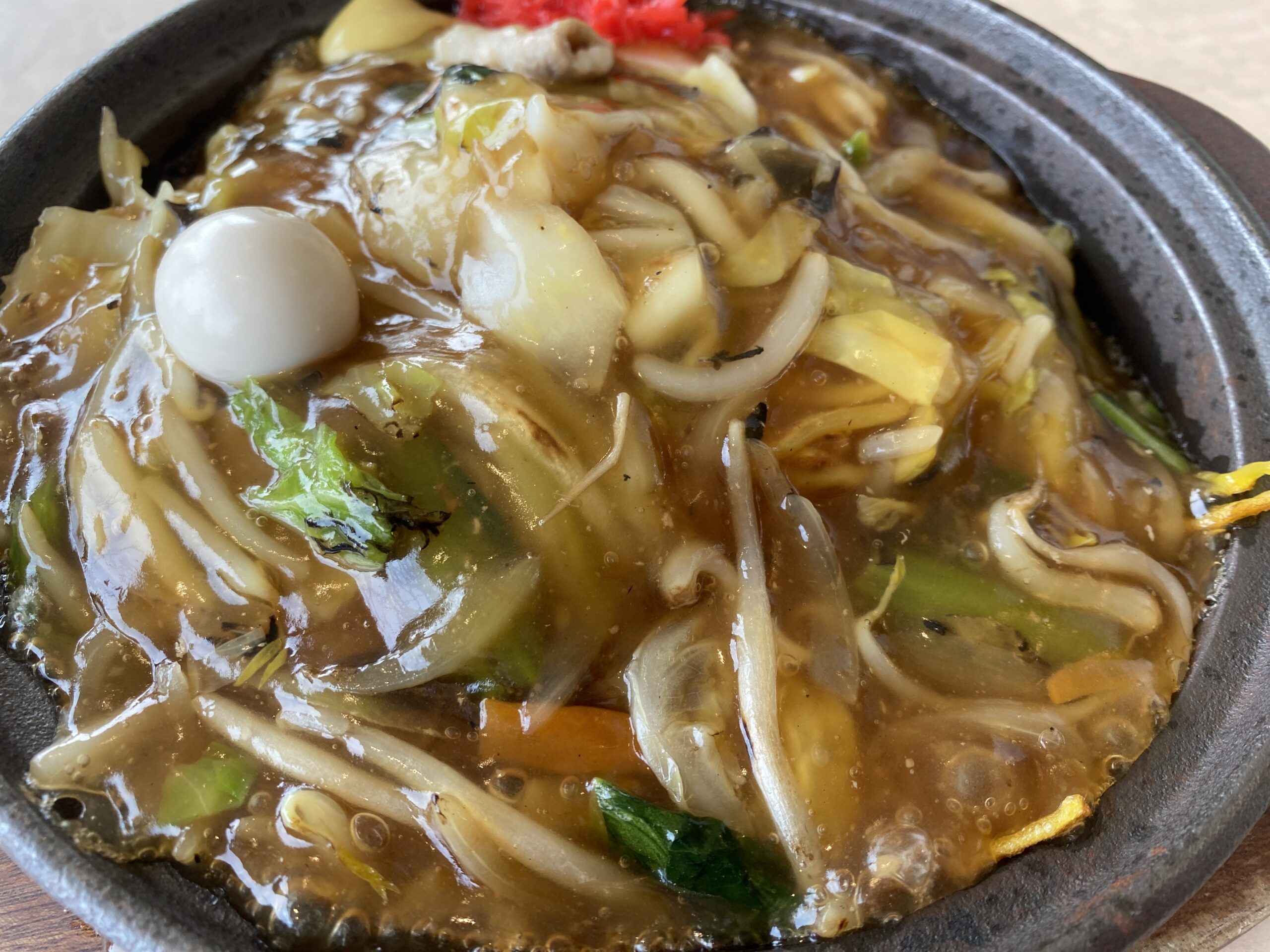 窓の外に海が広がる席に置かれた、湯気の立つあんかけ焼きそば